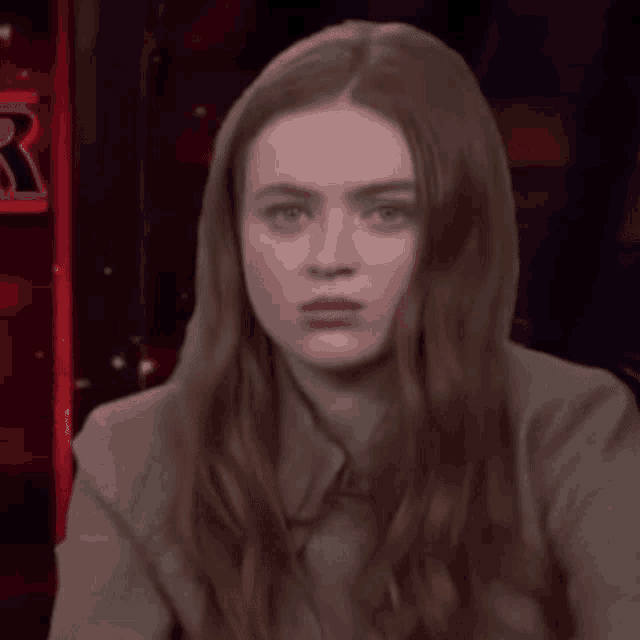 a woman with long red hair is wearing a hoodie and making a face .