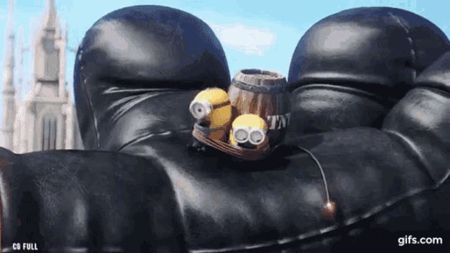two minions are sitting on top of a black leather couch