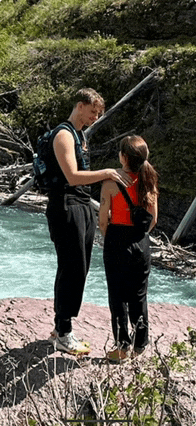 a man and a woman standing next to a river .