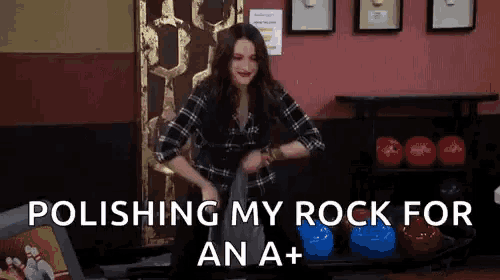 a woman is standing in a bowling alley holding a bowling ball and polishing her rock for an a+ .