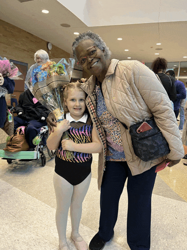 a little girl in a zebra print leotard holds a bouquet of flowers