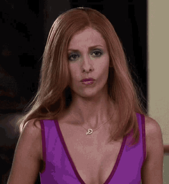 a woman with red hair is wearing a purple top and a necklace