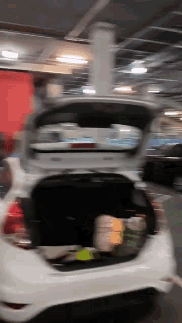 the trunk of a white car is filled with lots of groceries