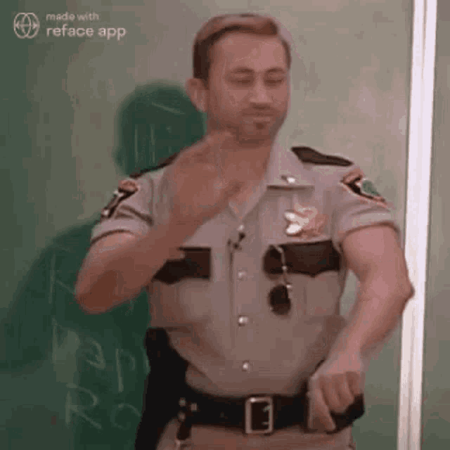 a man in a sheriff 's uniform is standing in front of a blackboard and giving a thumbs up .