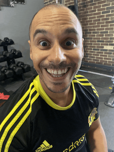 a man wearing a black and yellow adidas shirt