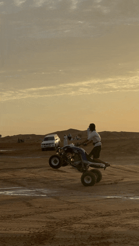 a man is doing a trick on a four wheeled vehicle in the desert