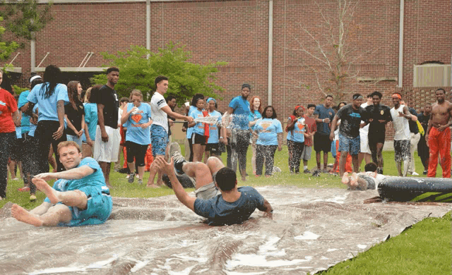 a group of people are playing in the water and one of them is wearing a shirt that says ' nc state ' on it