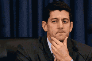 a man in a suit and tie is sitting in front of a microphone with his hand on his chin