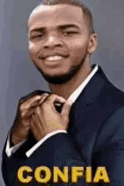 a man in a suit and tie is smiling while adjusting his tie .