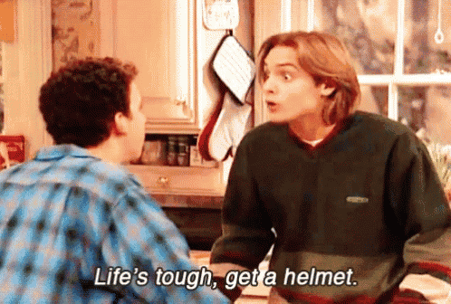 two men are talking in a kitchen and one of them says life 's tough get a helmet