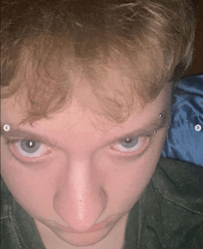 a close up of a person 's face with a piercing in the eyebrow