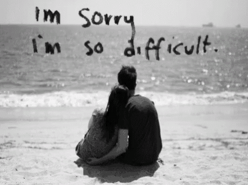 a black and white photo of a man and woman sitting on the beach with the words i 'm sorry i 'm so difficult