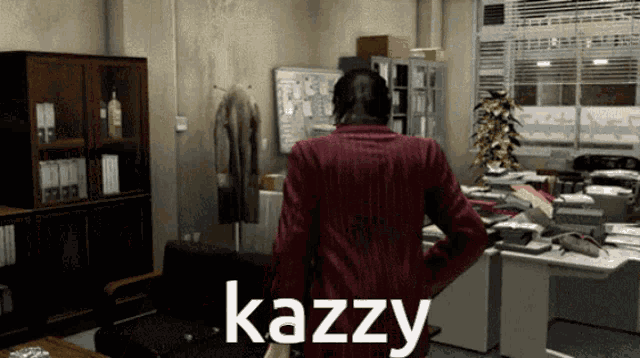 a man in a red jacket is standing in an office with kazzy written on the bottom