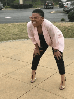 a woman wearing glasses and a pink jacket is kneeling down on the sidewalk