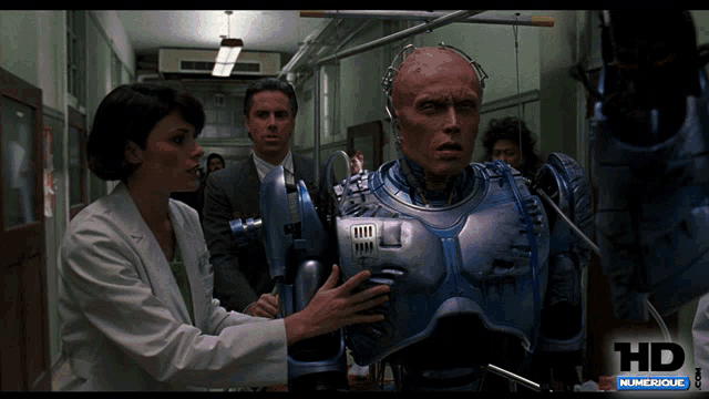 a man in a robotic suit is being examined by a woman and a man in a suit