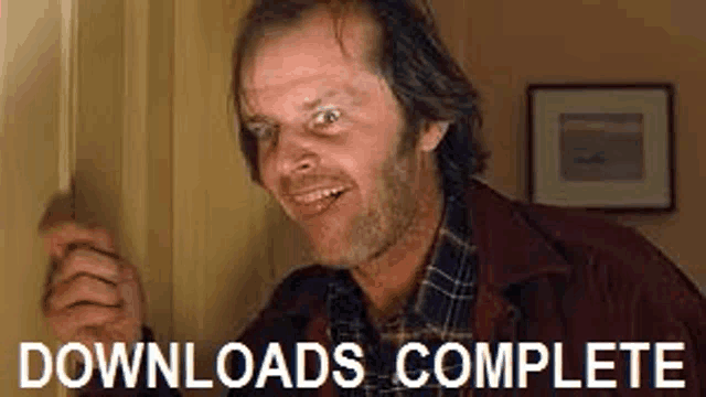 a man in a plaid shirt is standing in a doorway with the words `` downloads complete '' above him .