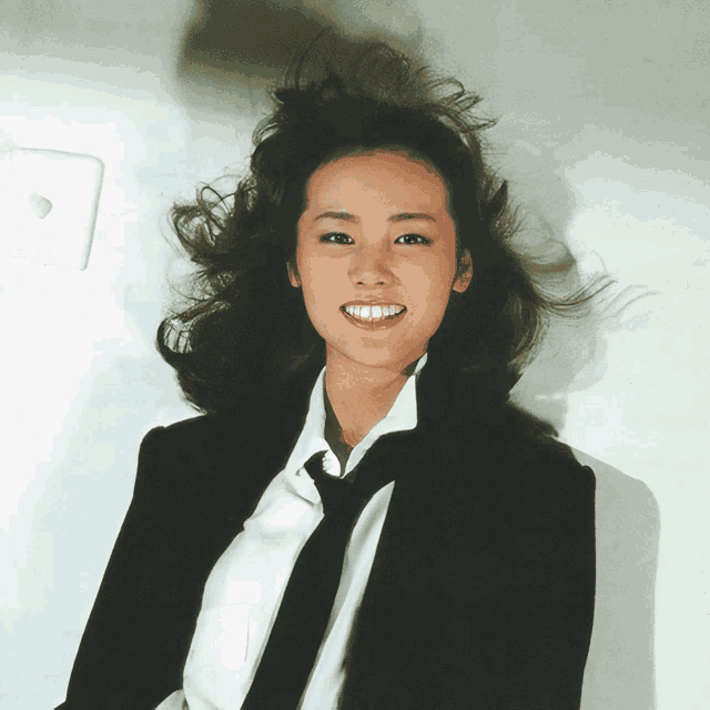 a woman wearing a black suit and tie smiles for the camera