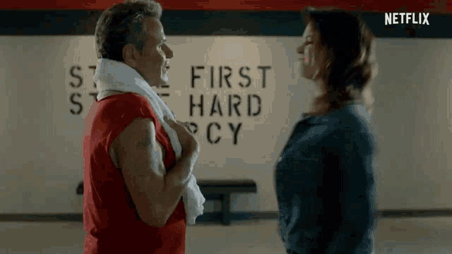 a man and a woman are standing next to each other in front of a wall that says first hard