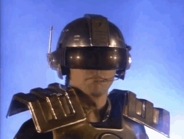 a man wearing a futuristic helmet and armor is looking at the camera .