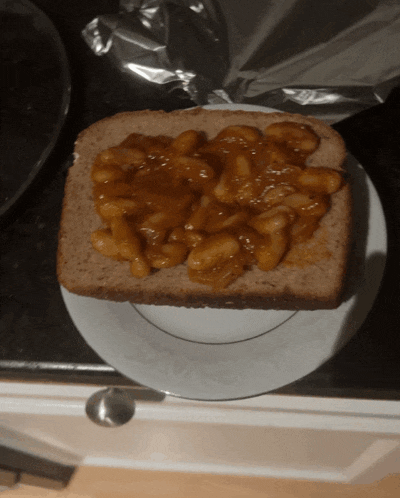 a slice of bread with baked beans on it on a white plate