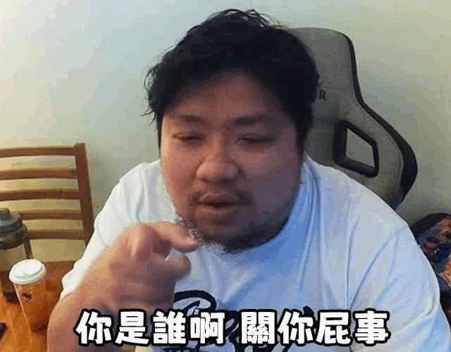 a man with a beard is sitting at a table making a funny face in chinese .