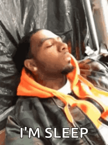 a man is sleeping on a bed with the words `` i 'm sleep '' written next to him .