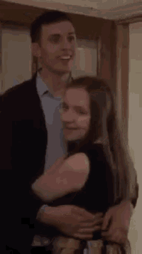 a man and woman are standing next to each other in a room .