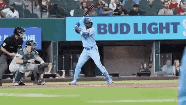 a baseball player is swinging a bat at a ball during a game in front of a bud light sign .