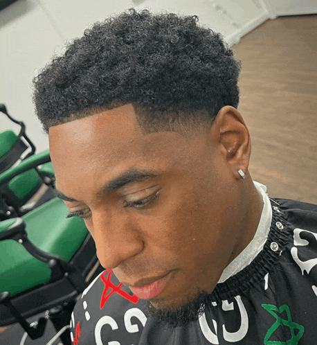 a man is getting his hair cut by a barber wearing a cape that says go