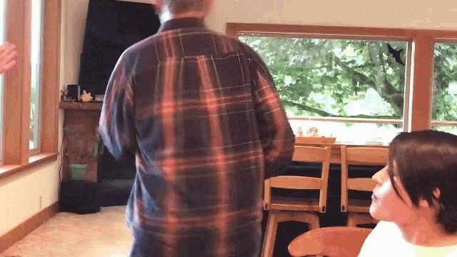 a man in a plaid shirt stands in front of a woman in a white shirt