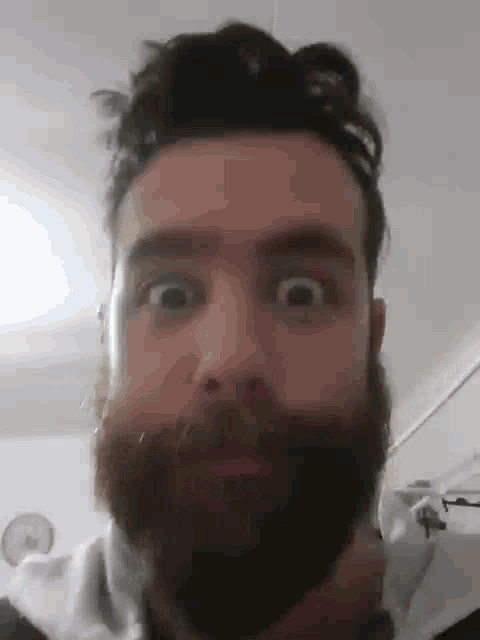 a man with a beard is making a funny face with his eyes closed .