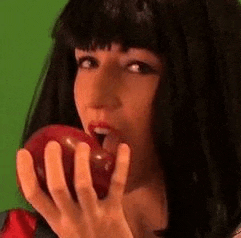 a woman is holding an apple in her hand and biting into it .