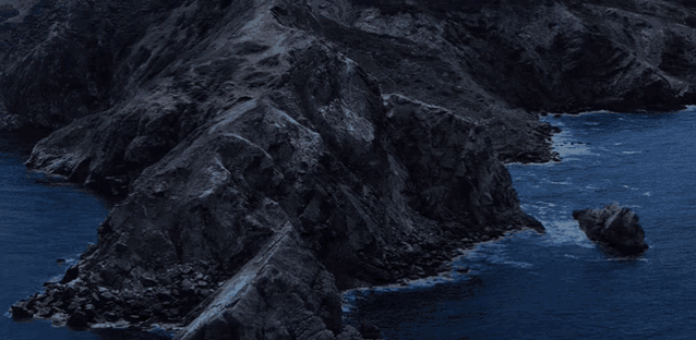 a rocky shoreline with a large rock in the middle of the ocean