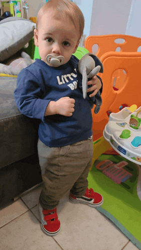 a little boy wearing a blue shirt that says little boy