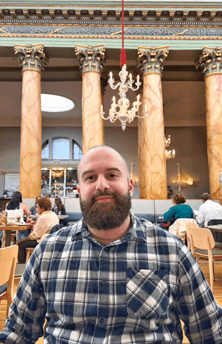 a man with a beard wearing a plaid shirt is sitting in a restaurant