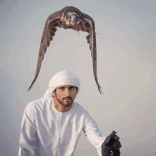 a man is holding a bird that is flying in the air above him