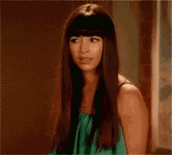 a woman with long hair and bangs wearing a green dress