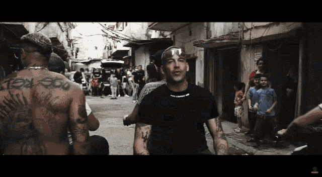 a man with a tattoo on his back stands in a crowded street