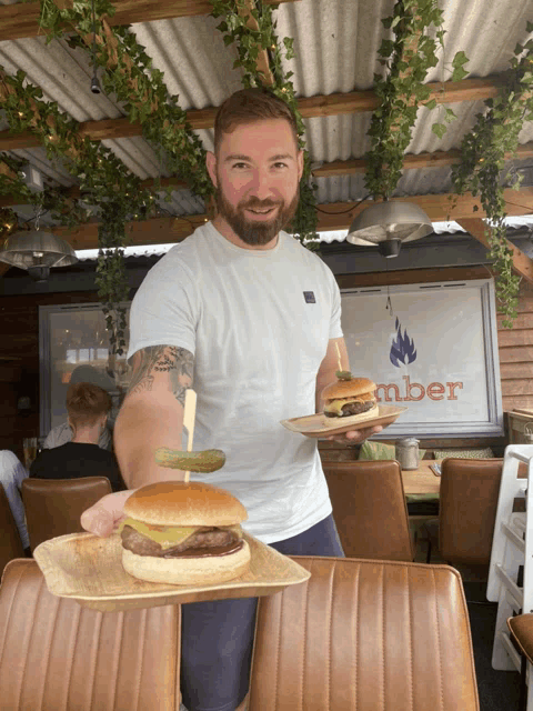 a man holding a tray of hamburgers in front of a sign that says mber