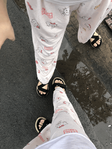 a person wearing hello kitty pajama pants and black sandals