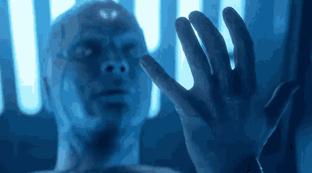 a close up of a man 's hand reaching out towards a glass wall .