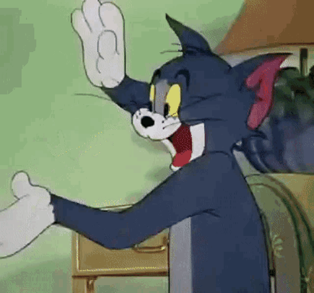 tom from the cartoon tom and jerry is waving his hand in a room .