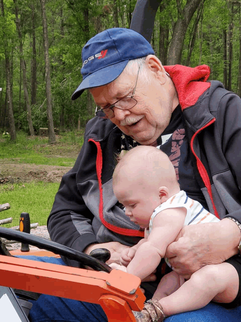 an older man holding a baby wearing a hat that says ' ross ' on it