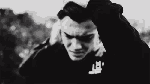 a black and white photo of a man covering his ears