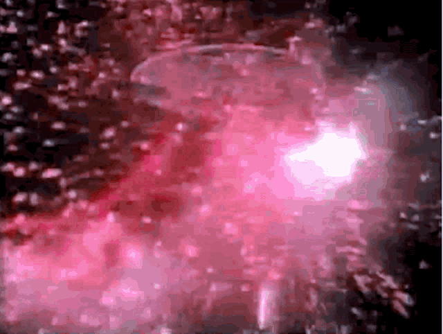 a close up of a pink light coming out of a glass of water .