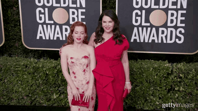 two women are posing for a picture on a red carpet in front of a sign that says golden globe awards