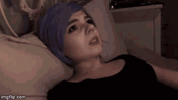 a woman with purple hair is laying on a bed with her eyes closed .
