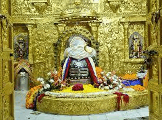 a large statue of a deity in a temple surrounded by flowers and gold decorations .