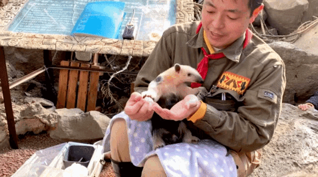 a man is holding a small animal with a patch on his jacket that says ' a / a '