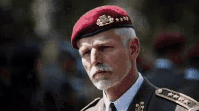a man in a military uniform is wearing a red beret with four stars on it